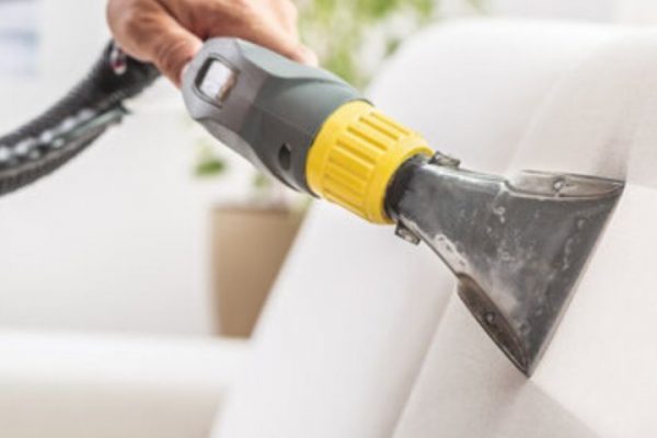Professional upholstery cleaning service in Guildford, showcasing a technician cleaning a sofa with advanced equipment for optimal results